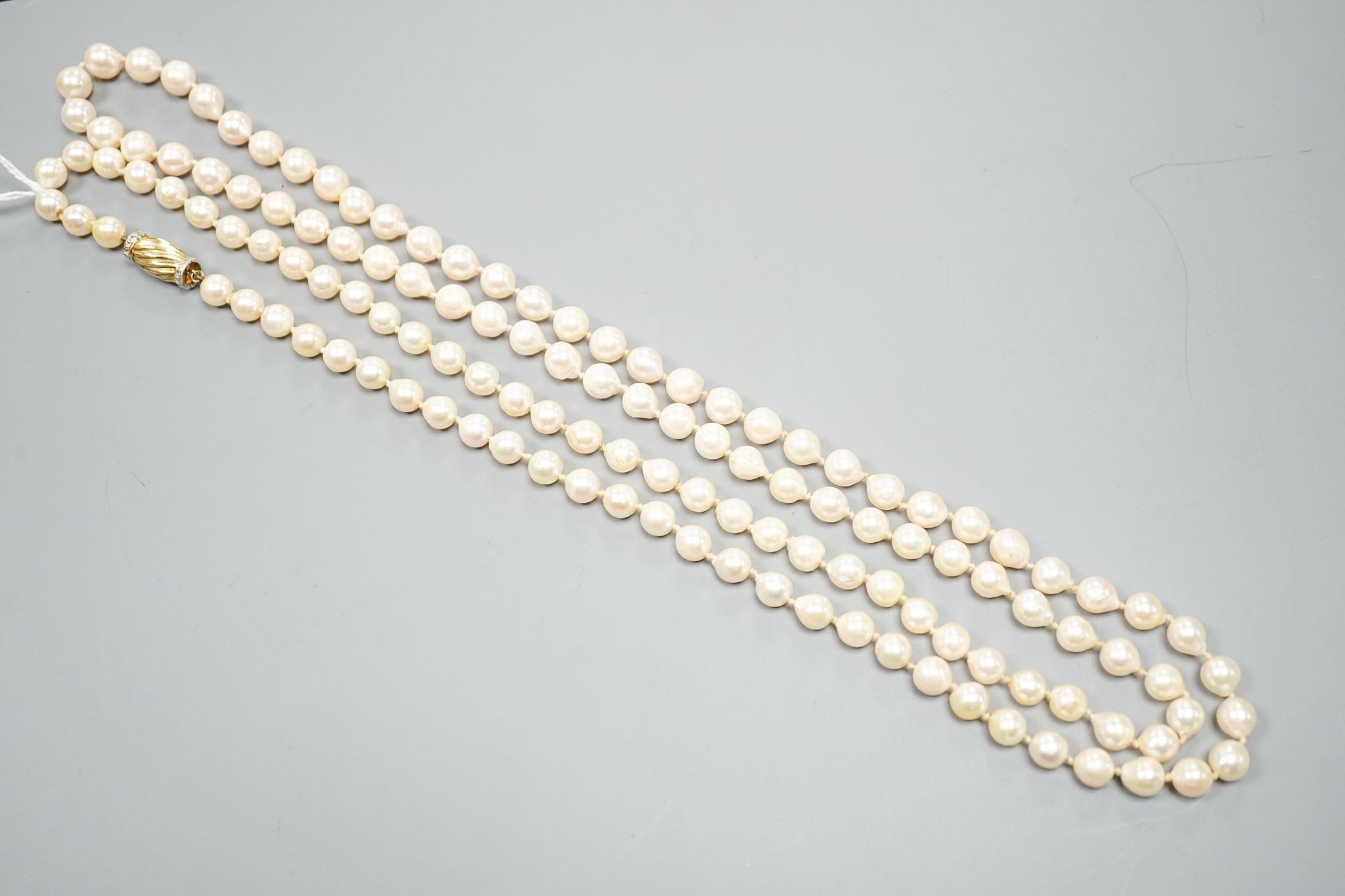 A modern long single strand cultured pearl necklace, with fluted 14k and diamond chip set clasp, 116cm.